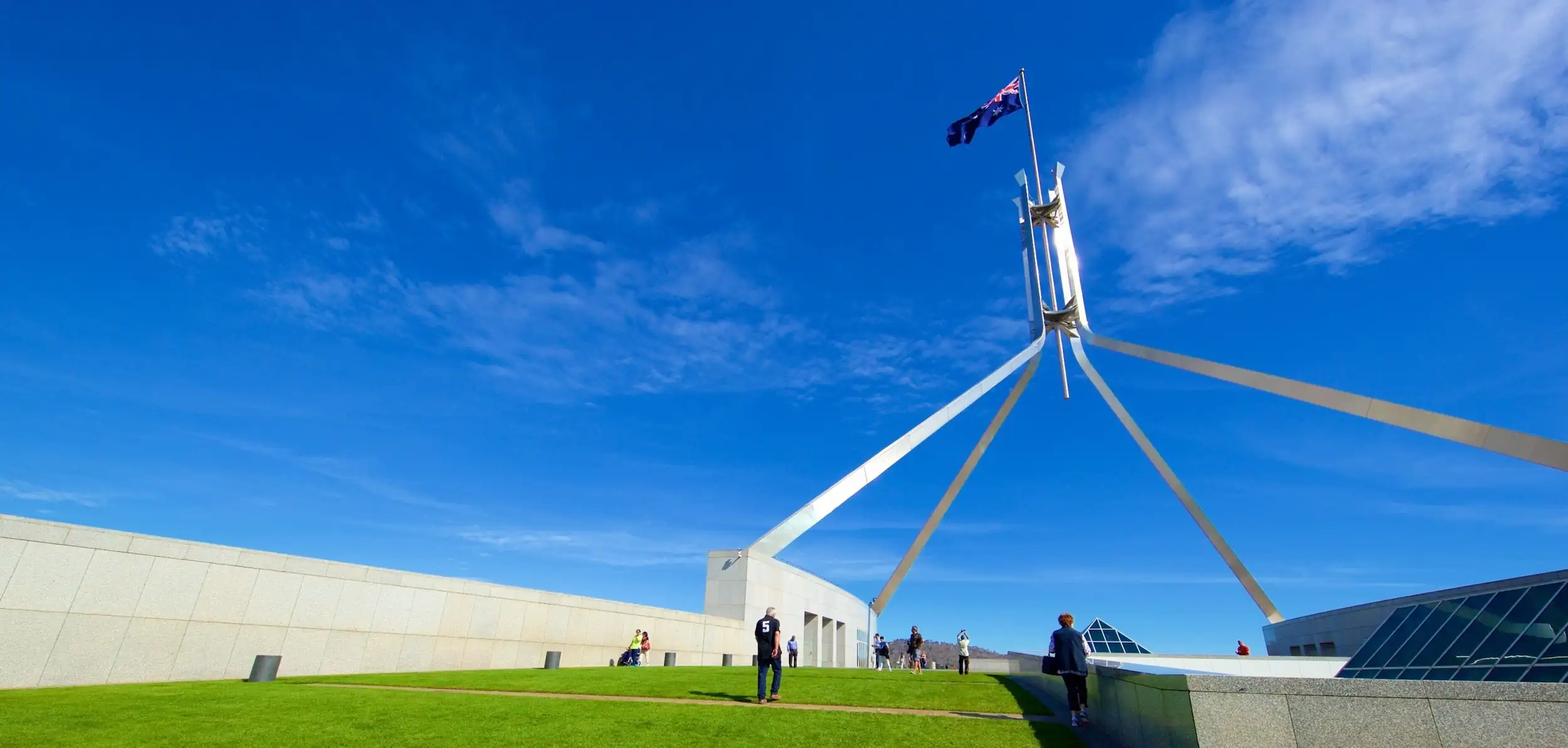 Australian Parliament House in Canberra with the flag flying against a blue sky