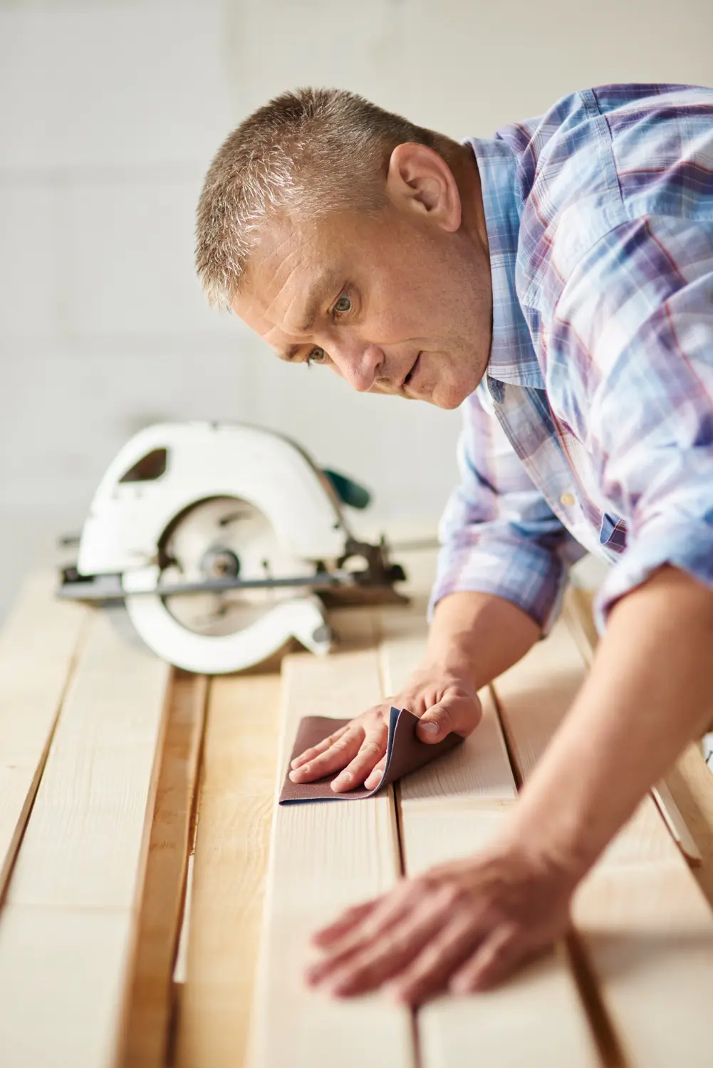 Canberra carpenter sanding timber planks with a circular saw on the bench