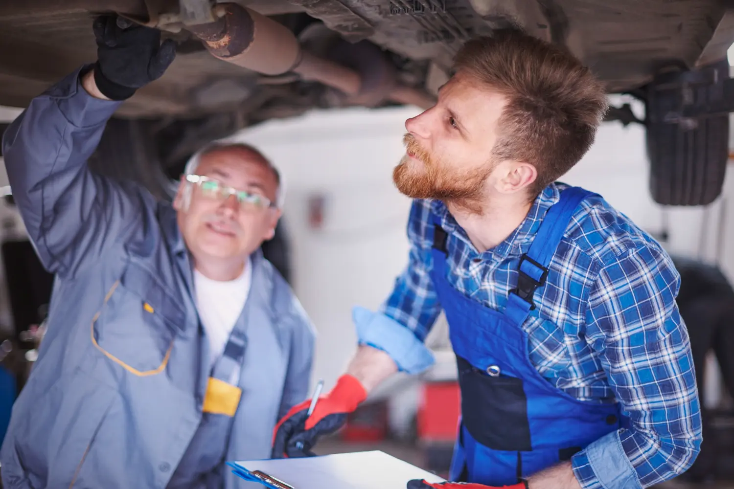 Two Canberra mechanics inspecting the underside of a vehicle on a hoist