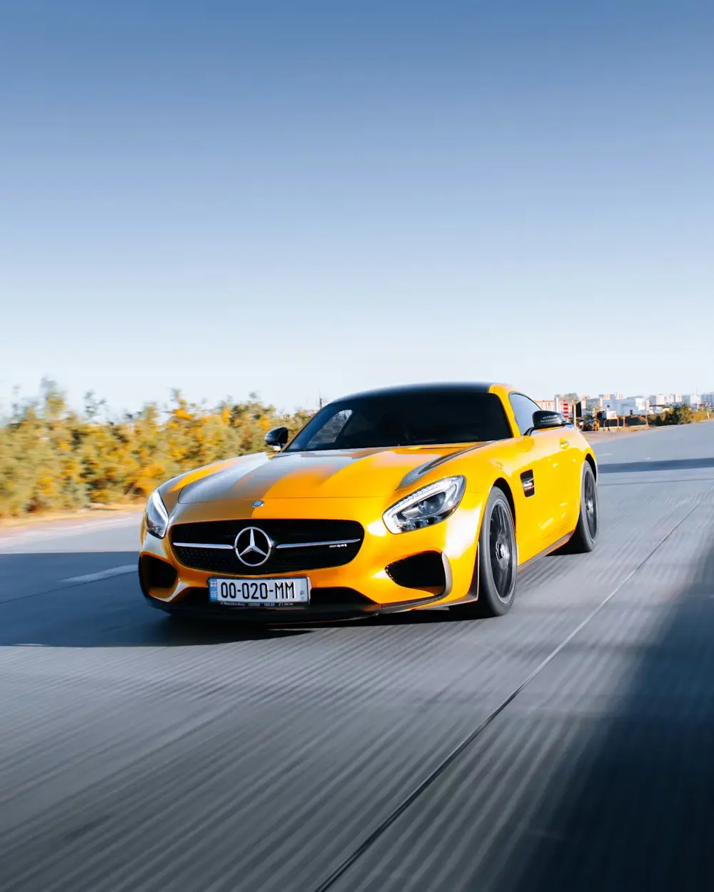 Bright yellow Mercedes-Benz sports car driving down an open road